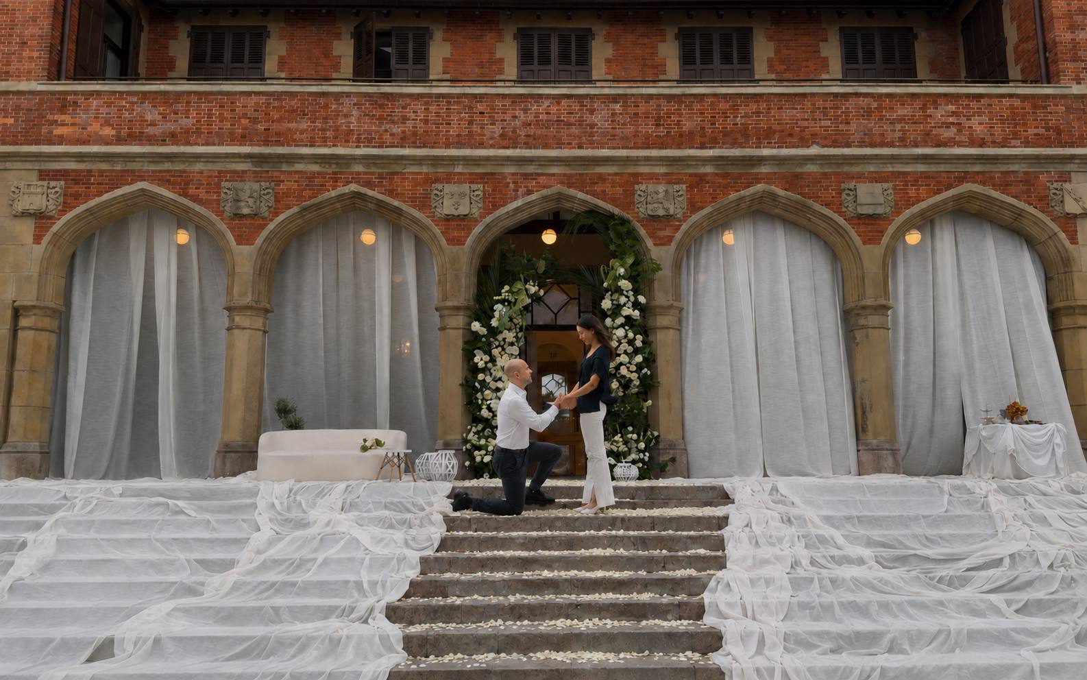Un hombre de rodillas pidiendo matrimonio bajo un arco floral en el Palacio de Miramar, San Sebastián